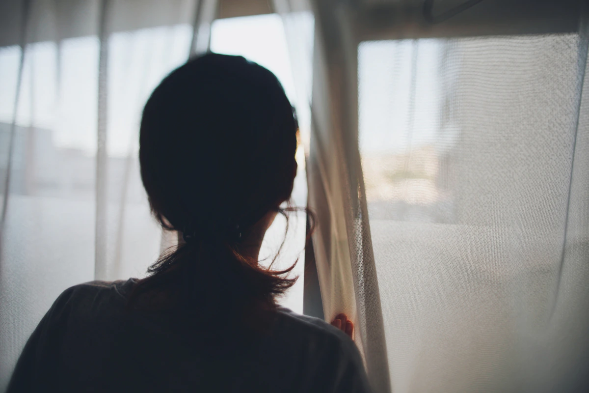 女性　暗い　背中　窓