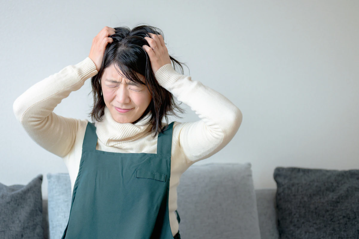 女性　頭を抱える　家　悩む